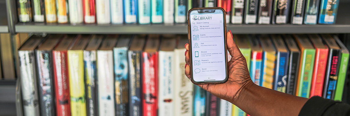 woman holding phone in front of bookshelves with library app loaded on screen