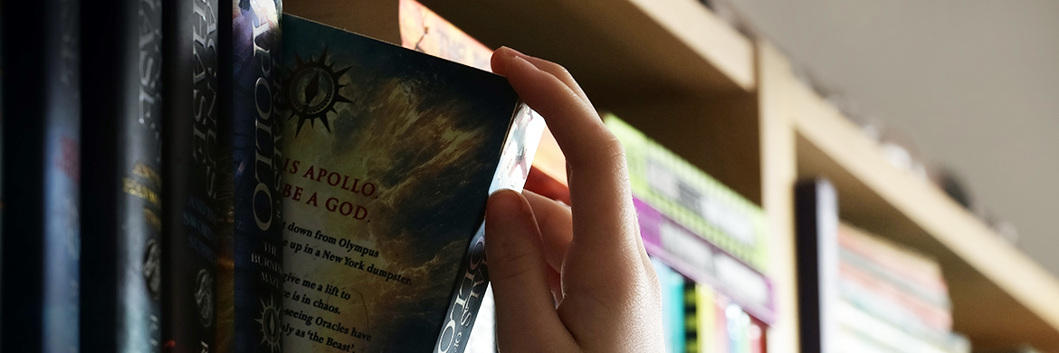 Teen taking book off shelf